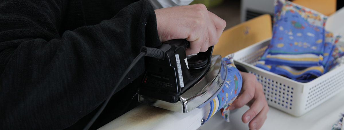 アイロンをかける作業中の施設利用者